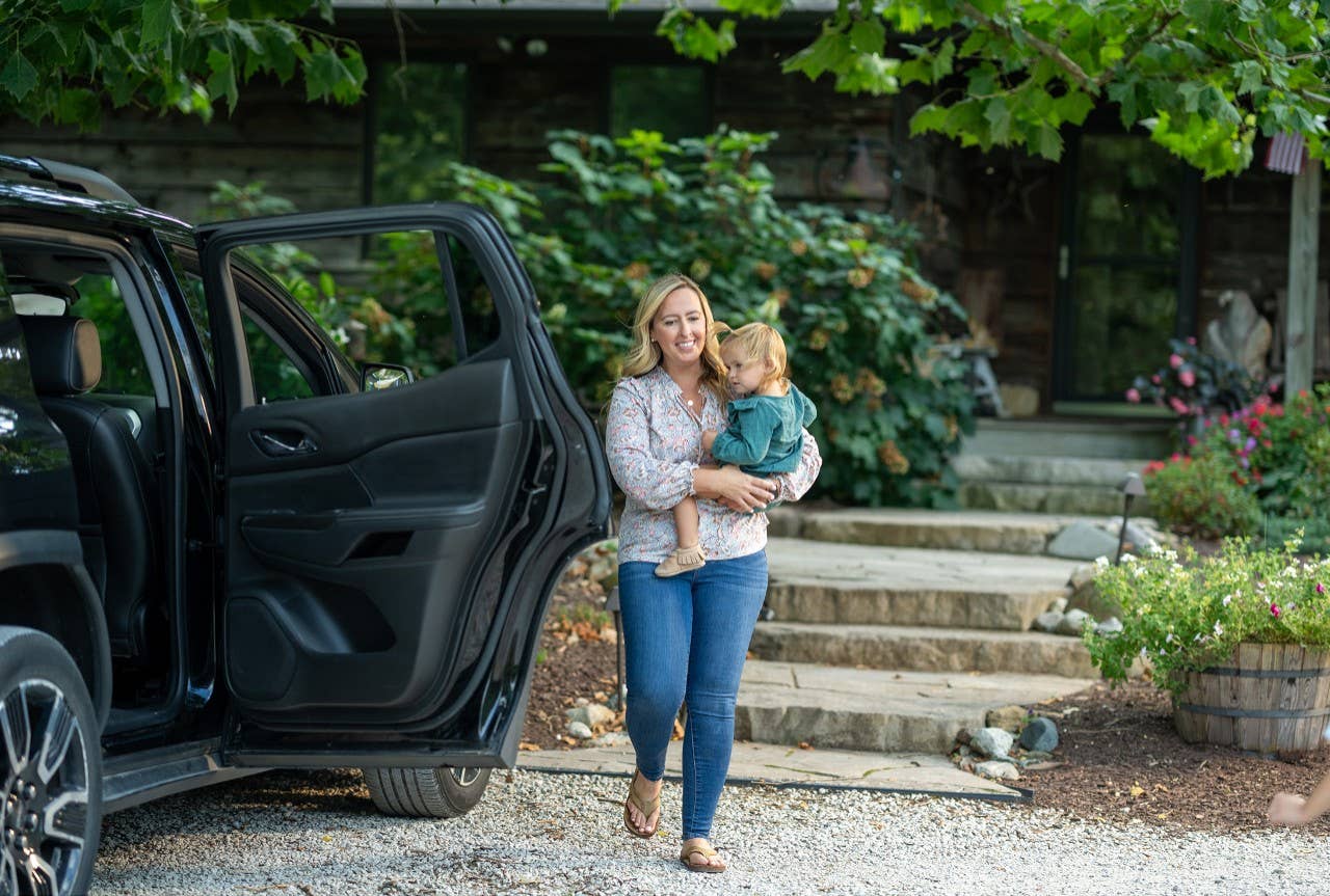 mom carrying daughter from home to car