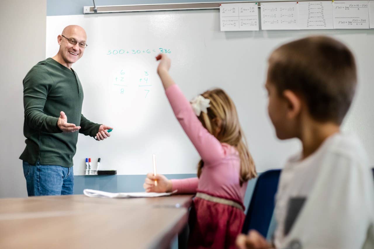 Teacher in classroom calling on student with raised hand