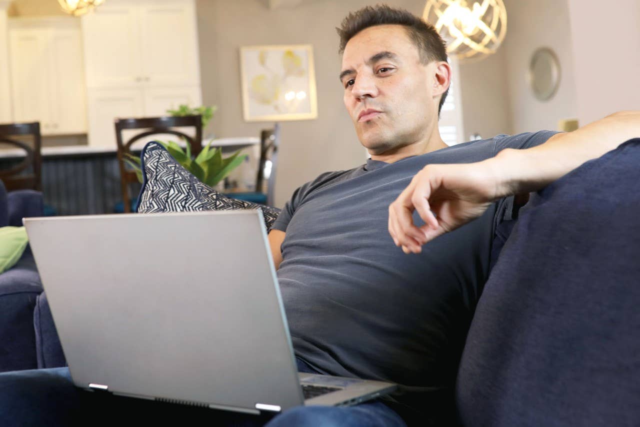 man sitting on a couch looking at laptop